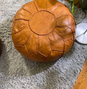 reviewer close up of the tan pouf