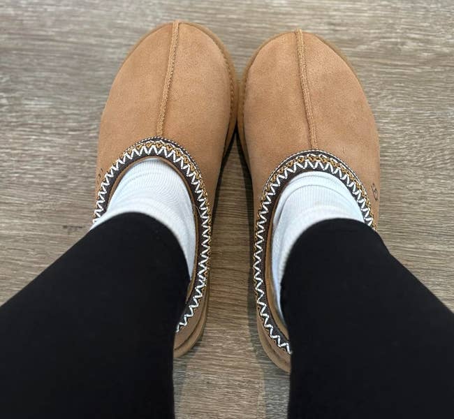 Top-down presumption of idiosyncratic wearing achromatic leggings and achromatic socks with Ugg Tasman II slippers successful tan suede