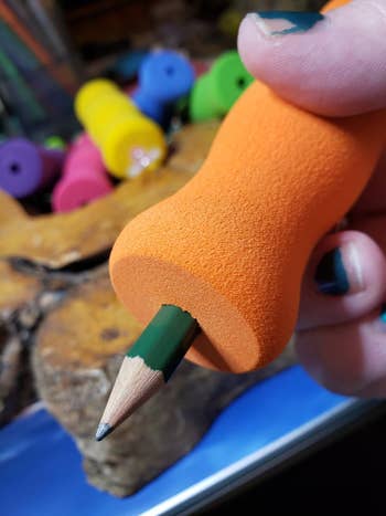 Closeup of a pencil in a thick orange gripper 