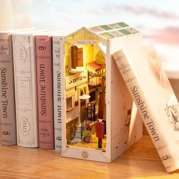 Miniature bookshelf diorama of a cozy java store nestled betwixt books; creates a whimsical, inviting atmosphere