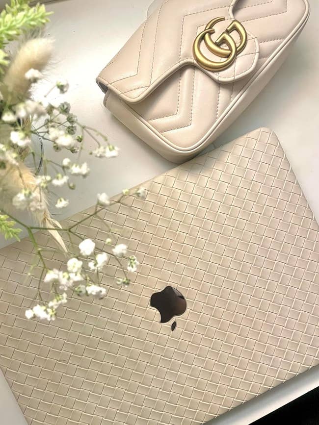 Laptop with woven texture cover, trendy decorator handbag, and decorative flowers, suggesting a stylish and modern buying theme