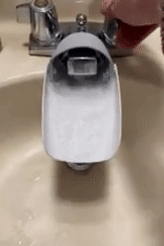 gif of reviewer turning on faucet showing the water steam on the extender