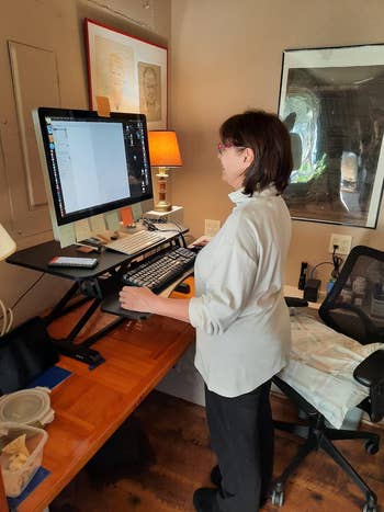 reviewer using sit-to-stand desk converter in the standing position