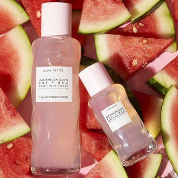 two of the bottles of toner in different sizes laying on watermelon slices