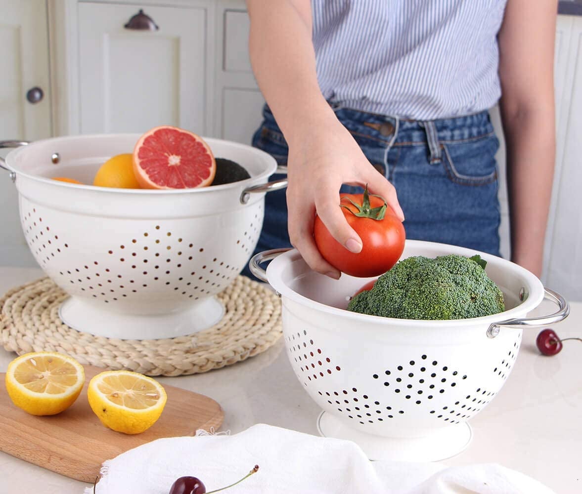 a model grabbing a tomato from the smaller collander