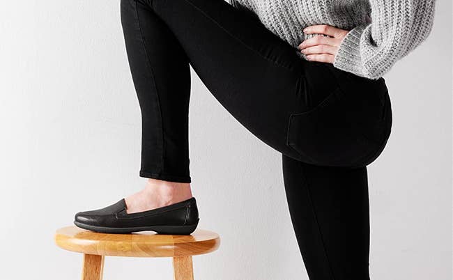 Model with their foot on a stool wearing the black loafer
