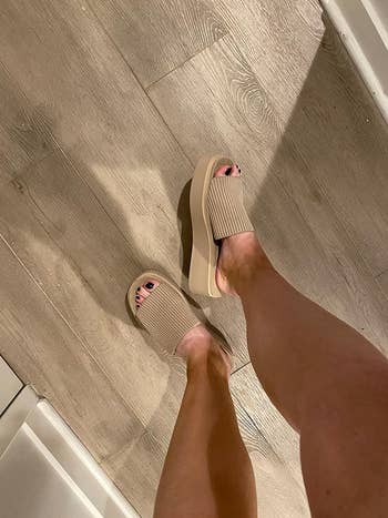Person wearing open-toe level    sandals with textured straps, lasting  connected  a woody  floor