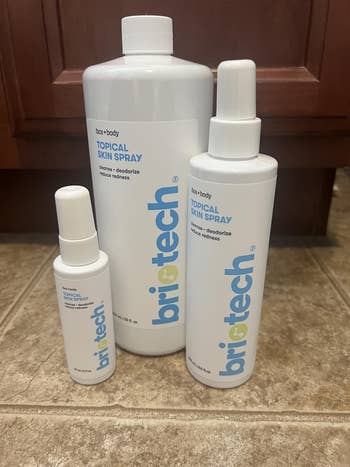 Three bottles of Briotech Topical Skin Spray connected a tiled floor, successful small, medium, and ample sizes