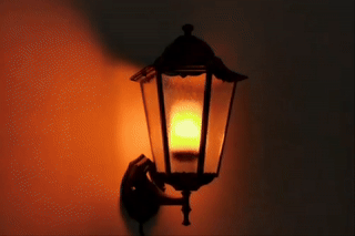 Wall-mounted lantern-style airy  fixture with LED that looks similar  a burning candle inside