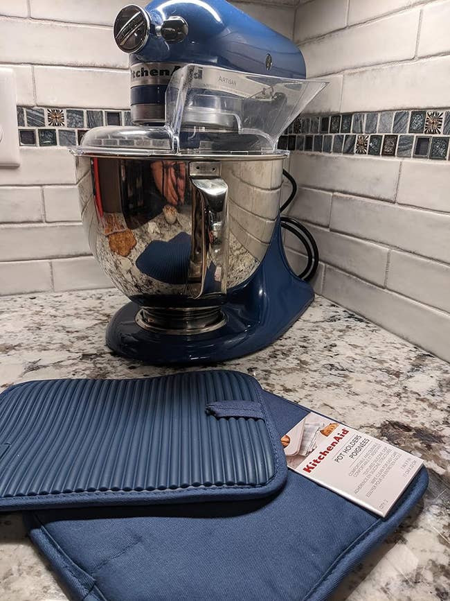 KitchenAid stand mixer on a counter next to a pair of blue silicone pot holders