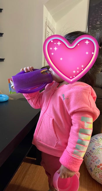 reviewer photo of child holding the purple container and sipping from it