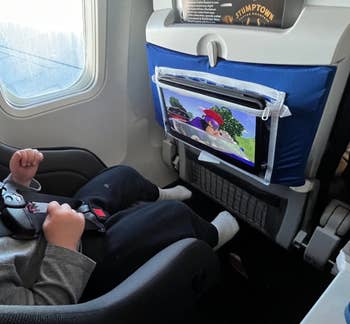 kid watching tablet on the back of airplane tray