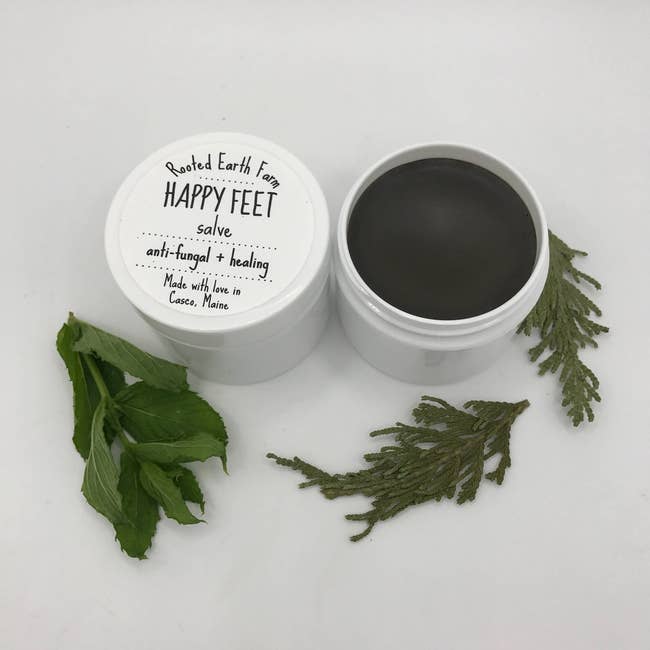Tub of Rooted Earth Farm Happy Feet salve next to opened tub of salve