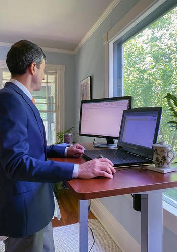 Reviewer standing and using brown wood-top desk