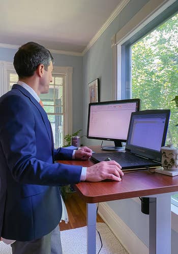 Reviewer standing and using brown wood-top desk