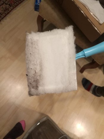 reviewer image of the dirty used pad on the head of the baseboard cleaning tool