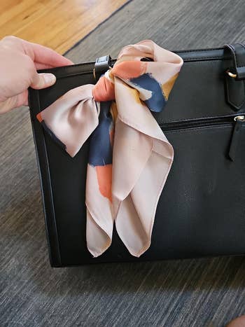 A manus  holding a achromatic  handbag adorned with a large, patterned bow. Ideal for style-focused buying  content
