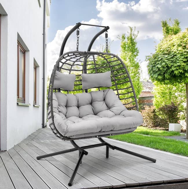 Outdoor ovum  seat  with cushioned seating connected  a patio, surrounded by greenery. Ideal for relaxation and leisure successful  plot  spaces