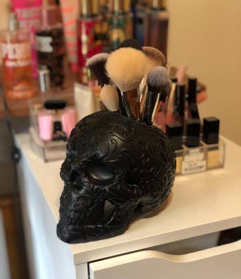 The skull in black filled with makeup brushes on a reviewer's vanity