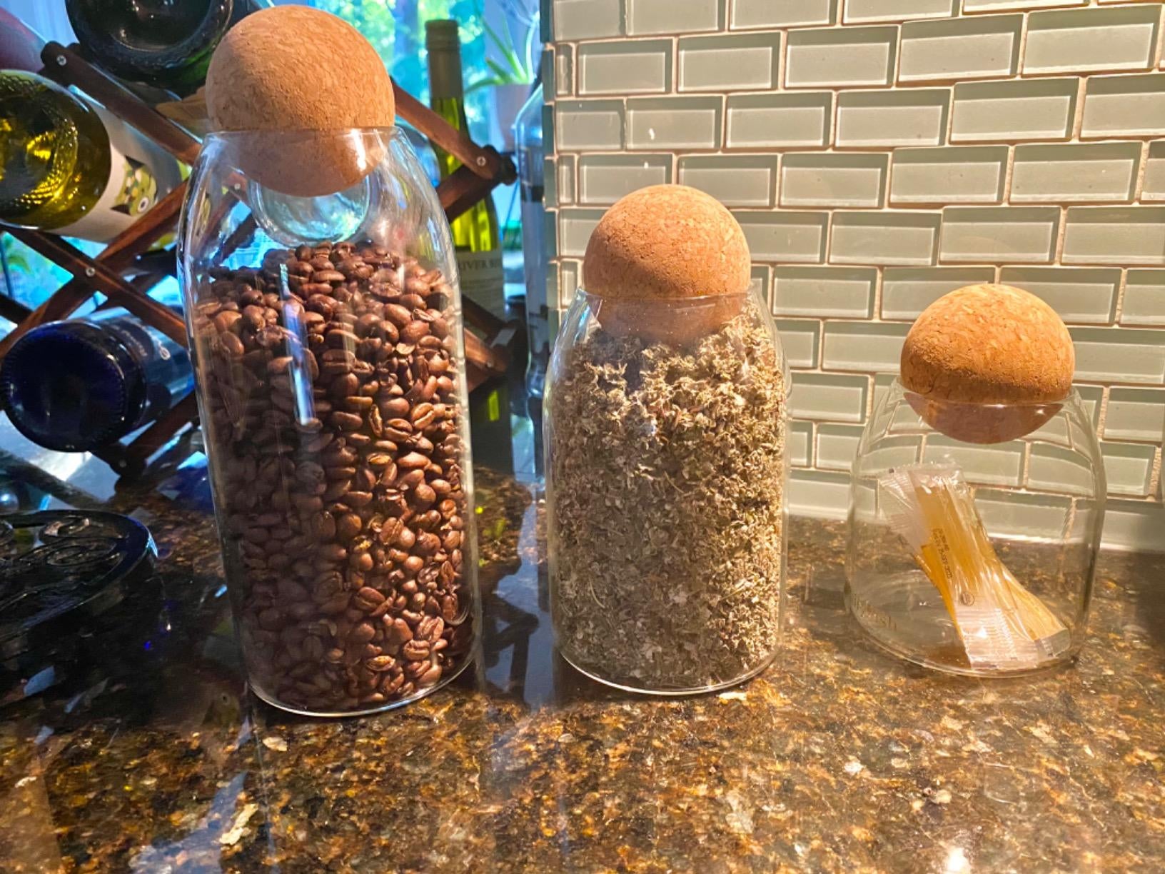 Glass storage jars with cork ball tops that contain dry ingredients