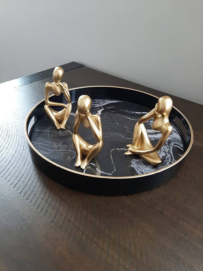 reviewer photo of three abstract human statuettes in a marble-printed tray