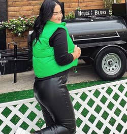reviewer wearing the neon green puffer vest over a black top and pants with white sneakers