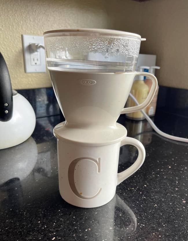 An OXO coffee dripper placed atop a mug on a kitchen counter