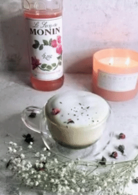 reviewer garnishing a rose latte  with the syrup in it 