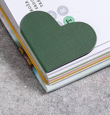 A green heart-shaped bookmark on the corner of a page in a book 