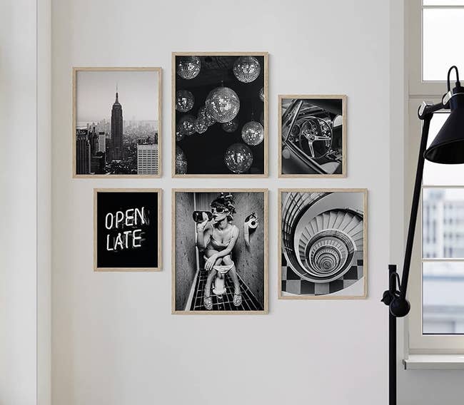 A gallery wall with various framed photographs including cityscapes and celestial bodies, beside a window