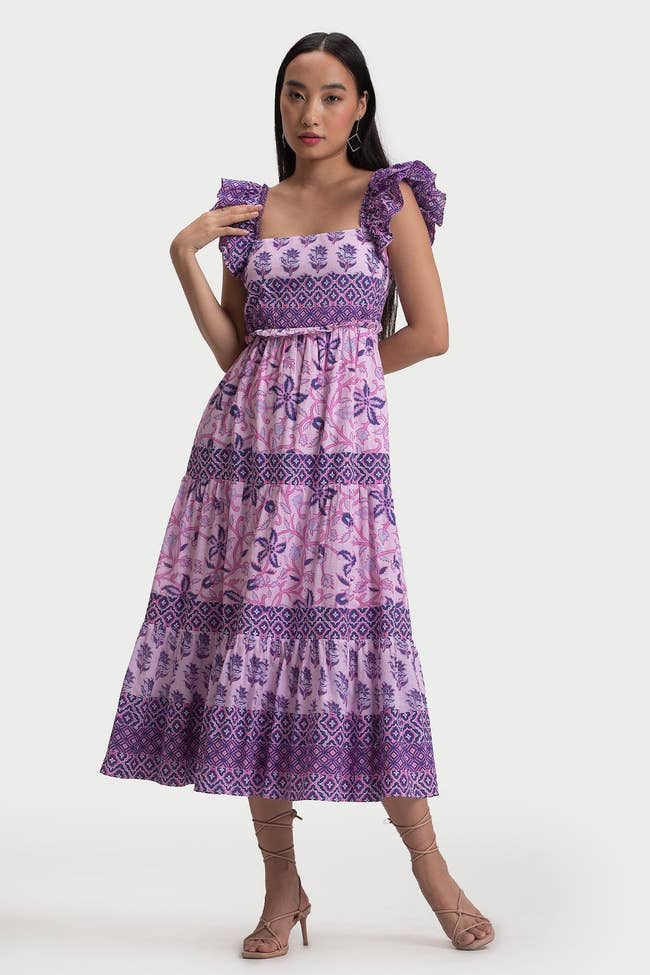 A model posing in the purple floral midid dress