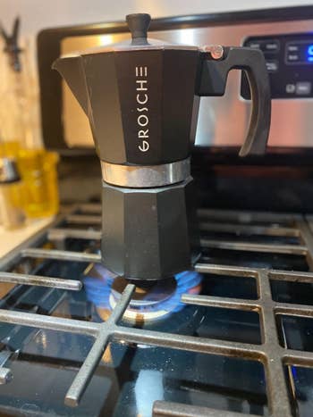 Black Grosche stovetop espresso maker on a gas stove with blue flame