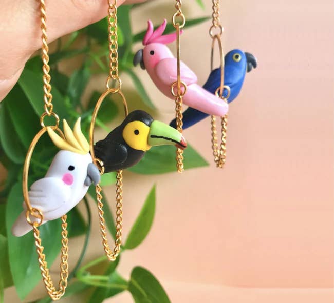 earrings with different types of clay birds (cockatoos, toucans, macaws) hanging from gold chain perch