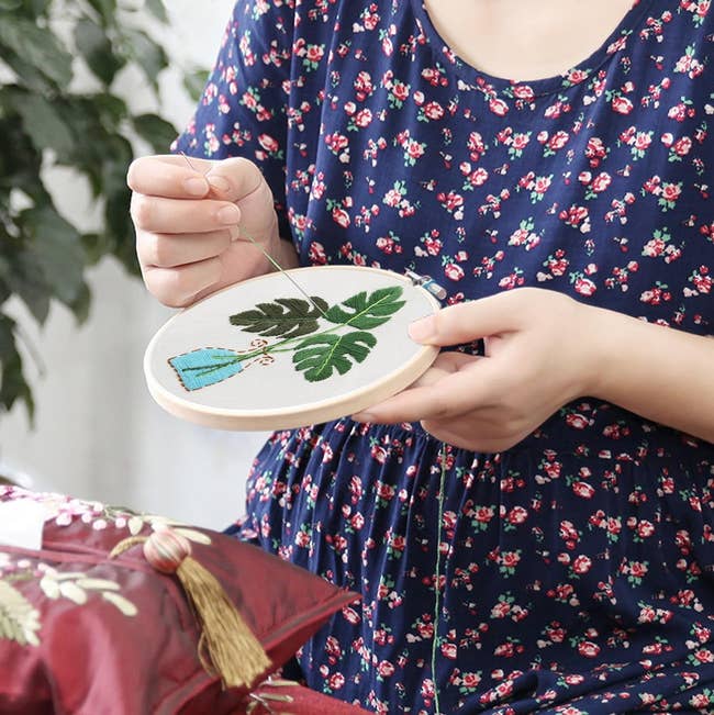 Model embroidering flowers into a hoop 