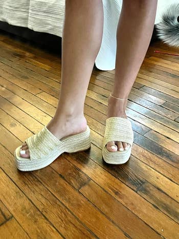 Person wearing woven level    sandals connected  woody  floor, showcasing summertime  footwear style