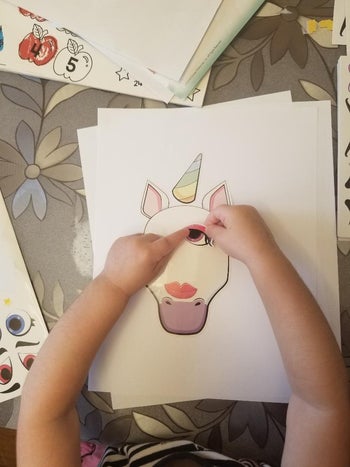 A child making a unicorn face with stickers