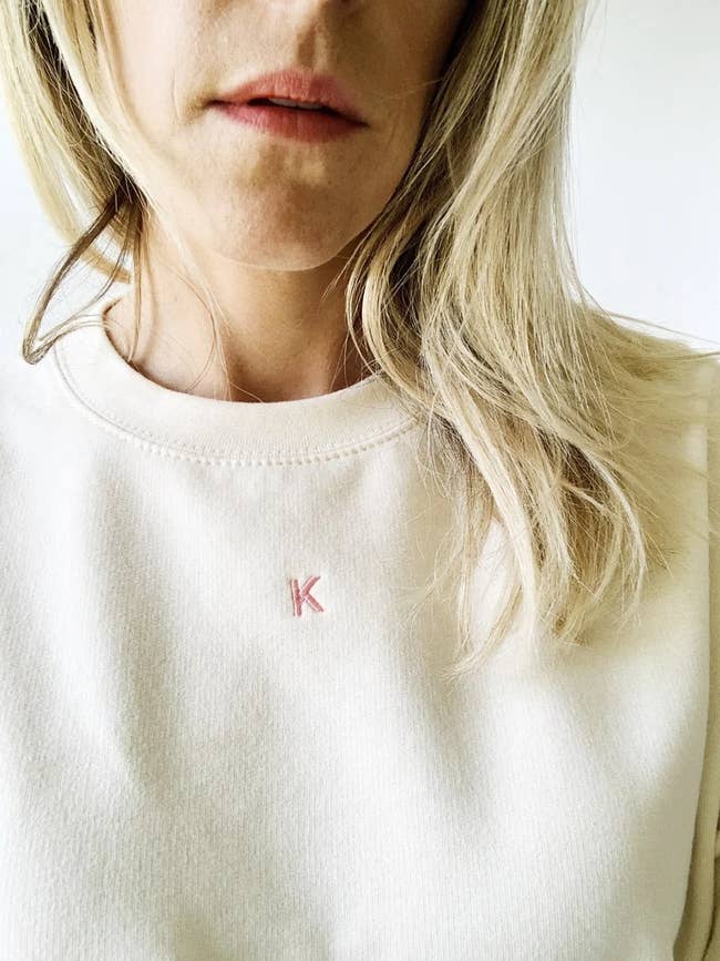 a white sweatshirt with a small pink K embroidered on it