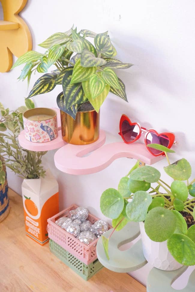 a close up of the pink shelf with plants and sunglasses sitting on top