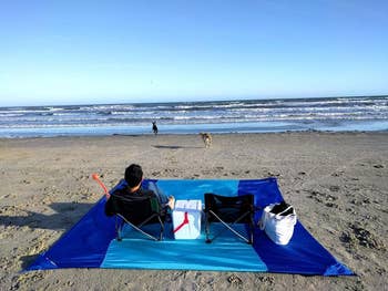 reviewer photo sitting on blue beach mat on the beach
