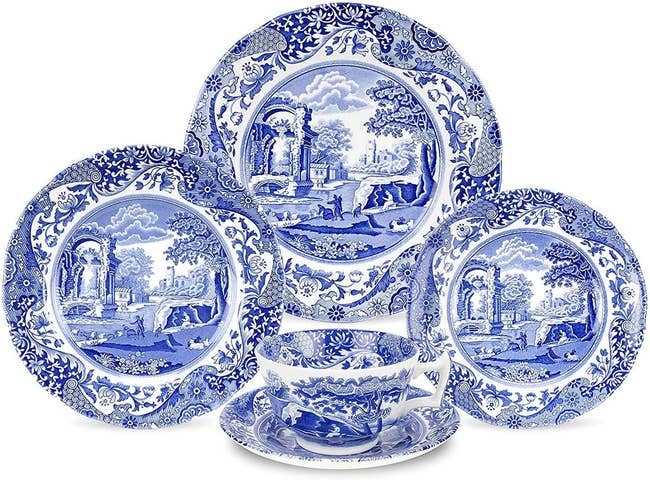 Several plates with matching village pattern beside teacup 