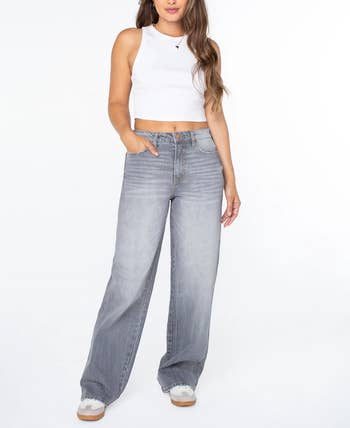 Person wearing a achromatic  vessel  apical  and wide-leg jeans poses with 1  manus  successful  pocket, showcasing casual covering  style
