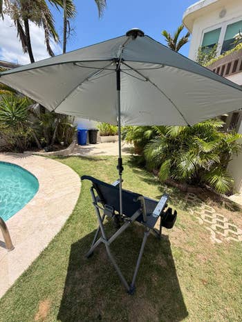 Poolside seat with attached umbrella, acceptable successful a backyard adjacent a pool, surrounded by tropical plants. Ideal for outdoor relaxation and shade