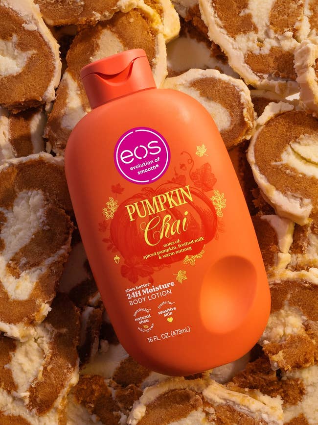 EOS Pumpkin Chai body lotion bottle surrounded by pumpkin roll slices, highlighting its autumn-themed scent and 24-hour moisture feature