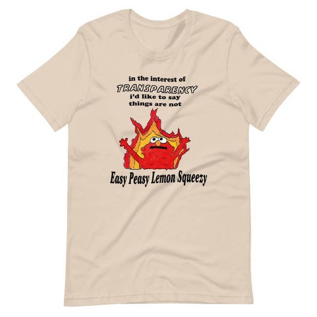 a cream-colored shirt with an illustration of Elmo in front of flames that says 