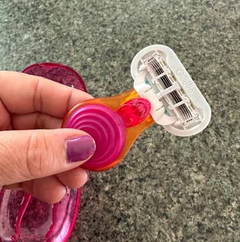 Hand holding a razor with a swirl grip  and multi-blade head, resting connected  a countertop