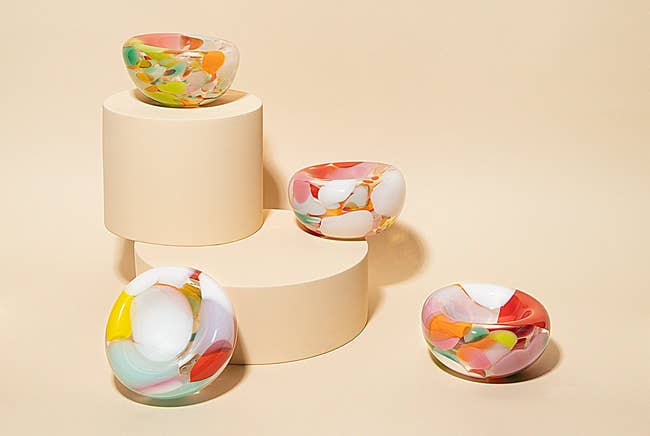 four glass ashtrays with different color splotches on them 