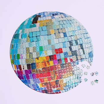 Round puzzle with a vibrant mosaic pattern, partially incomplete with missing pieces shown beside it