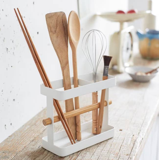 white utensil holder holding wooden kitchen utensils