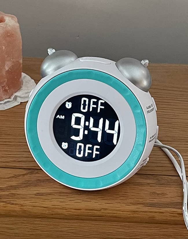 A white retro style ringing alarm clock with a digital round face displayng the time 