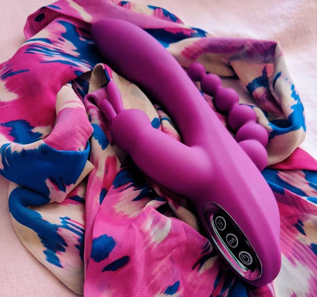 Pink triple-stimulating vibrator on pink multicolor scarf